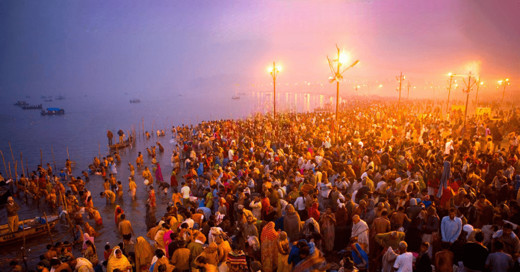 Kumbh Mela gathering at dusk with illuminated riverbank